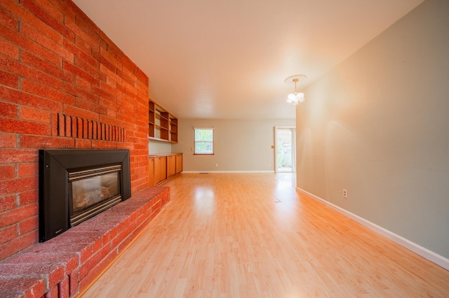 unfurnished living room featuring hardwood / wood-style floors, a fireplace, and a notable chandelier