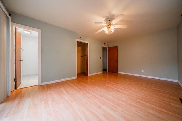 unfurnished bedroom with ceiling fan, a closet, light wood-type flooring, and a spacious closet