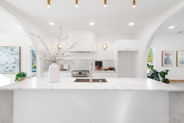 kitchen featuring white cabinetry, sink, an island with sink, and light stone counters