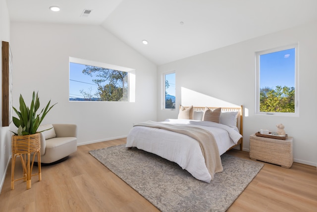 bedroom with multiple windows, vaulted ceiling, and light wood-type flooring