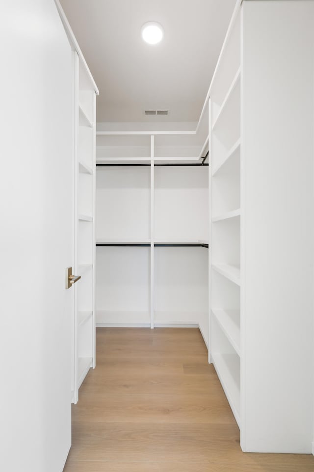 walk in closet with light hardwood / wood-style flooring