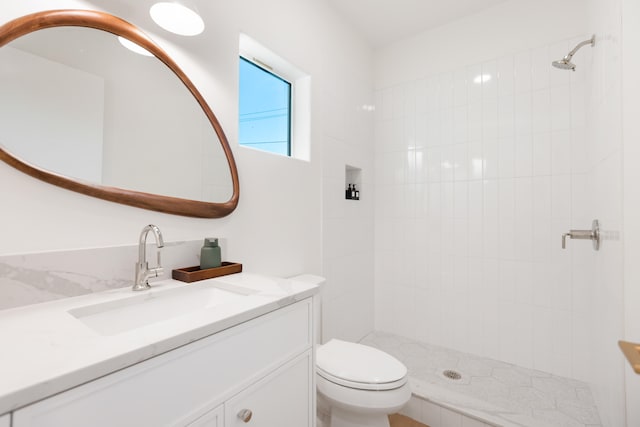 bathroom featuring vanity, toilet, and a tile shower