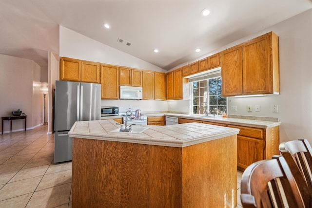 kitchen featuring lofted ceiling, a kitchen island with sink, tile counters, light tile patterned flooring, and appliances with stainless steel finishes