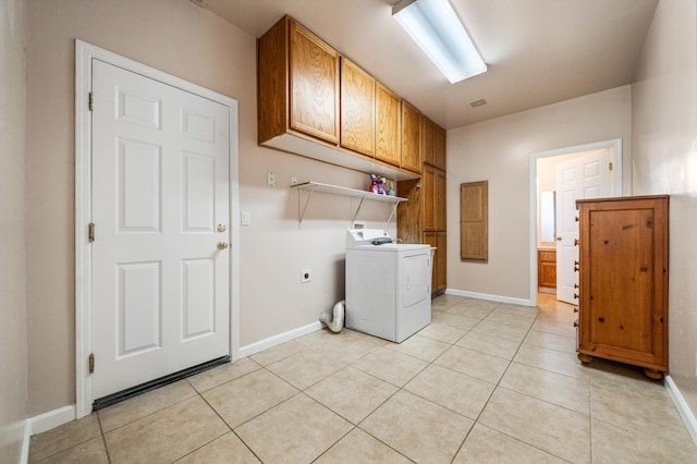 clothes washing area featuring washer / dryer, cabinets, and light tile patterned flooring