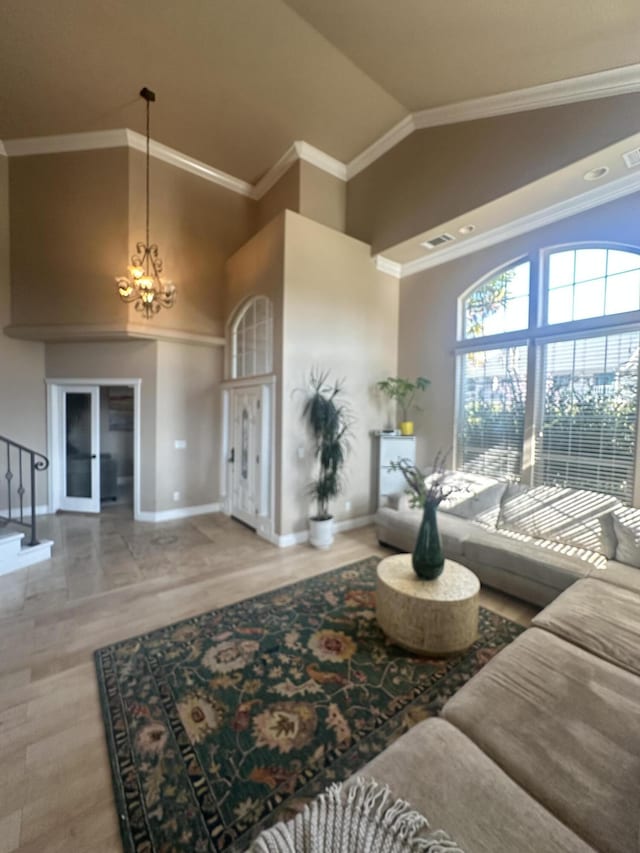 living room featuring baseboards, stairway, ornamental molding, an inviting chandelier, and high vaulted ceiling