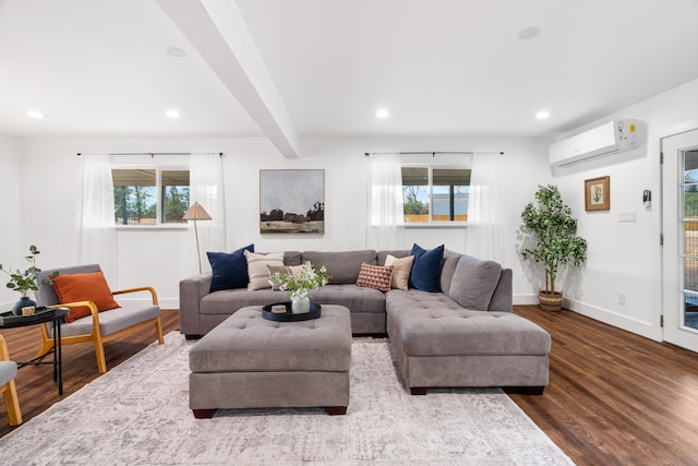 living room featuring a healthy amount of sunlight, an AC wall unit, beamed ceiling, and hardwood / wood-style floors