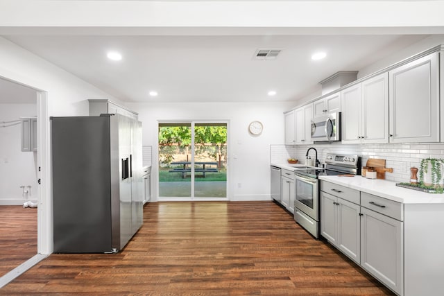 kitchen with dark wood-type flooring, appliances with stainless steel finishes, sink, and decorative backsplash