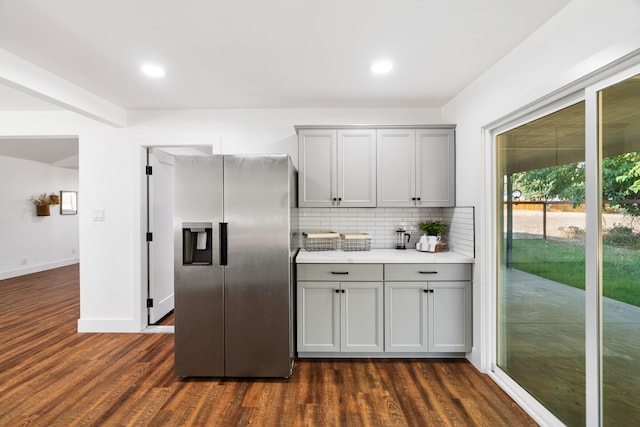 kitchen featuring decorative backsplash, stainless steel refrigerator with ice dispenser, gray cabinetry, and dark hardwood / wood-style flooring