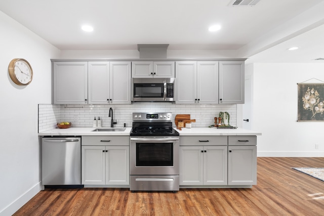 kitchen featuring stainless steel appliances, sink, light wood-type flooring, and gray cabinets