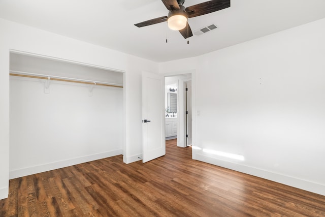 unfurnished bedroom with dark hardwood / wood-style flooring, a closet, and ceiling fan