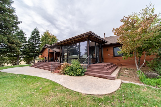 rear view of house featuring a lawn and a sunroom