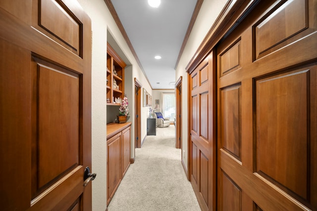 corridor with light carpet, ornamental molding, and built in features