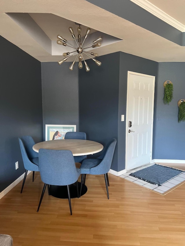 dining area with hardwood / wood-style flooring, a tray ceiling, and an inviting chandelier