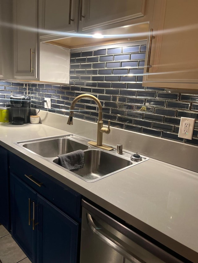 kitchen with dishwasher, tasteful backsplash, blue cabinetry, and sink