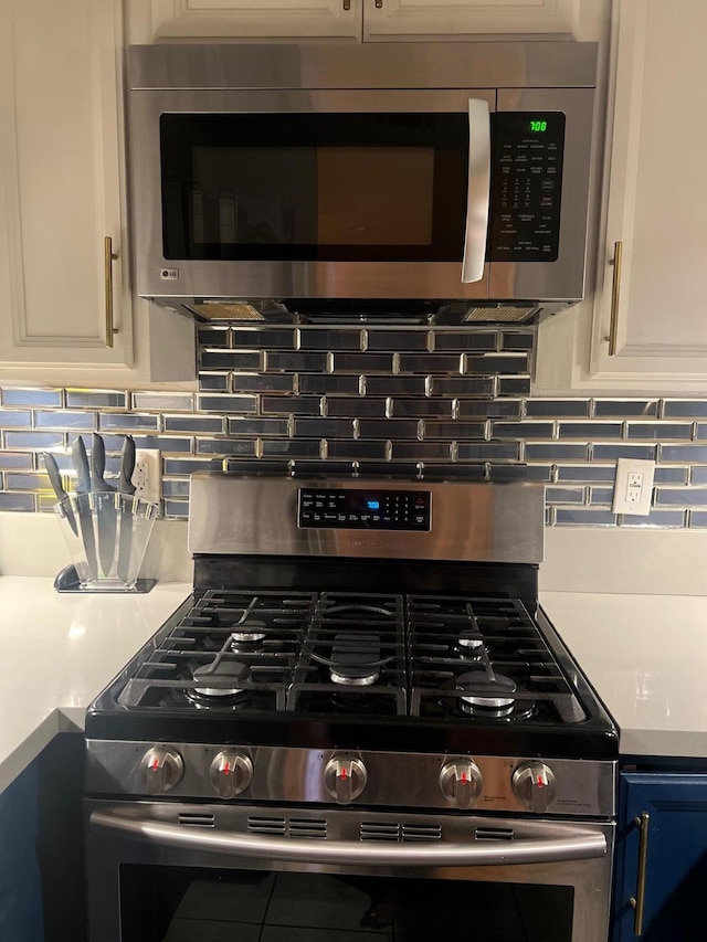 details with white cabinets, blue cabinetry, backsplash, and appliances with stainless steel finishes