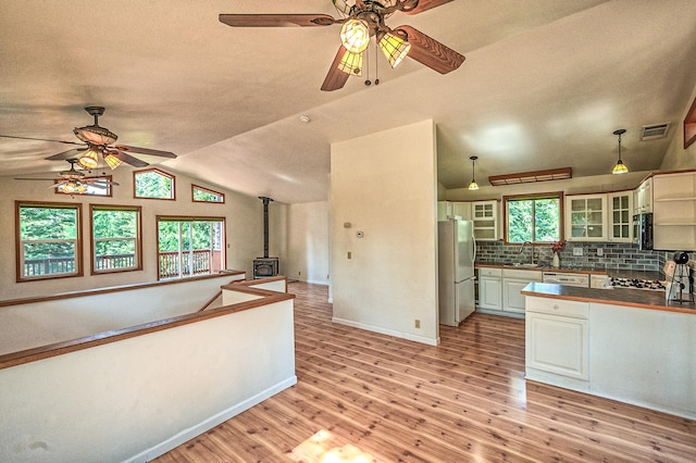 kitchen featuring light hardwood / wood-style flooring, a wood stove, stainless steel fridge, and hanging light fixtures