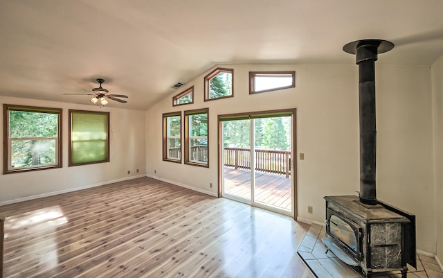 unfurnished living room featuring light hardwood / wood-style floors, a wood stove, lofted ceiling, and ceiling fan