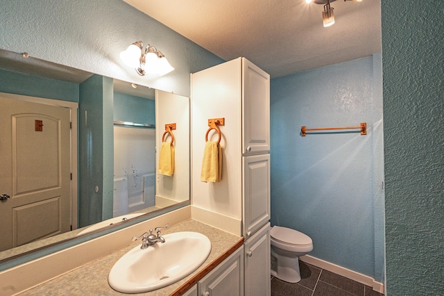 bathroom featuring vanity, toilet, a textured ceiling, and tile patterned flooring