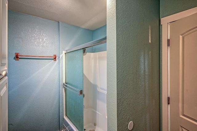 bathroom with a textured ceiling and an enclosed shower