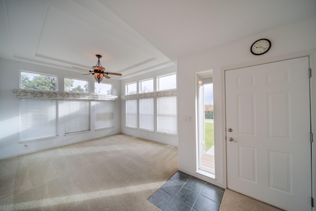 carpeted entrance foyer featuring ceiling fan and a tray ceiling