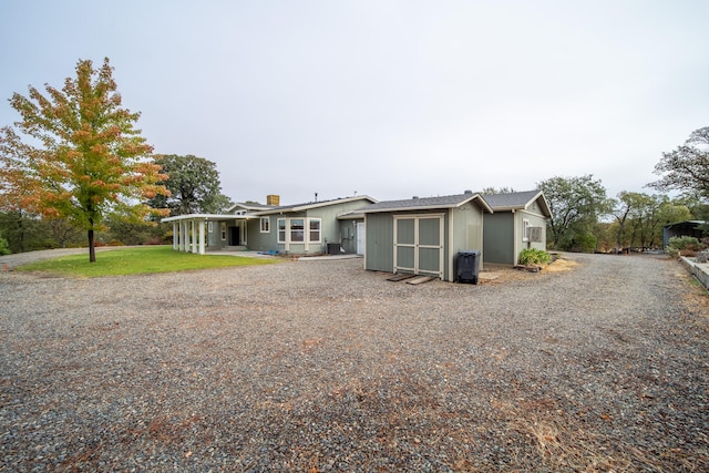 back of house with a shed and a yard