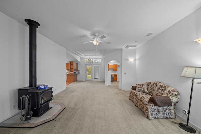 living room featuring a wood stove, light colored carpet, and ceiling fan