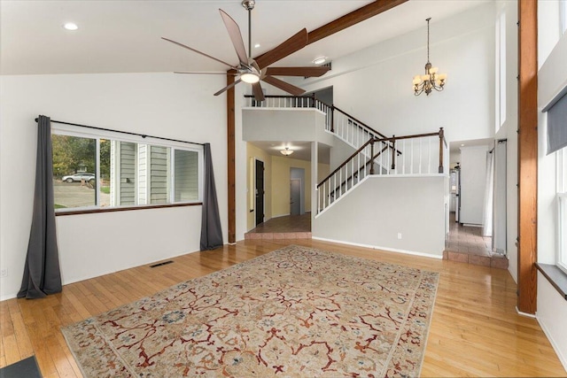 living room with ceiling fan with notable chandelier, high vaulted ceiling, beam ceiling, and light wood-type flooring