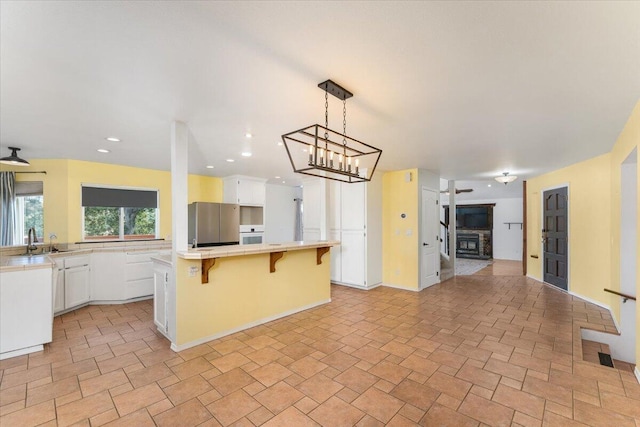 15540 China Rapids Dr, Red Bluff, CA 96080 - kitchen with light countertops, a sink, a breakfast bar, a kitchen island, and white cabinetry