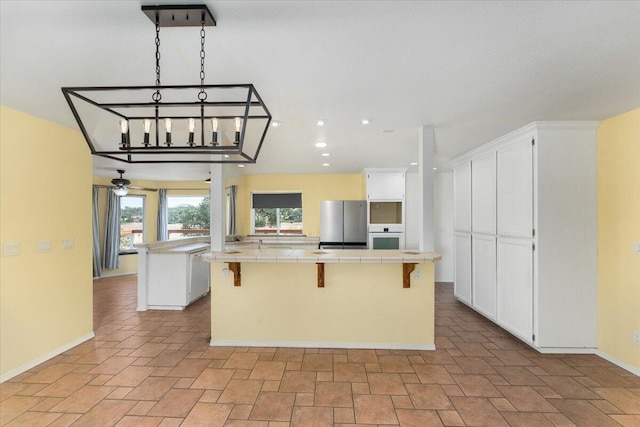 15540 China Rapids Dr, Red Bluff, CA 96080 - kitchen with tile counters, a spacious island, freestanding refrigerator, white oven, and white cabinetry