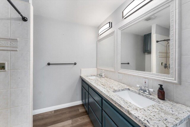 15540 China Rapids Dr, Red Bluff, CA 96080 - bathroom with double vanity, wood finished floors, baseboards, decorative backsplash, and a tile shower