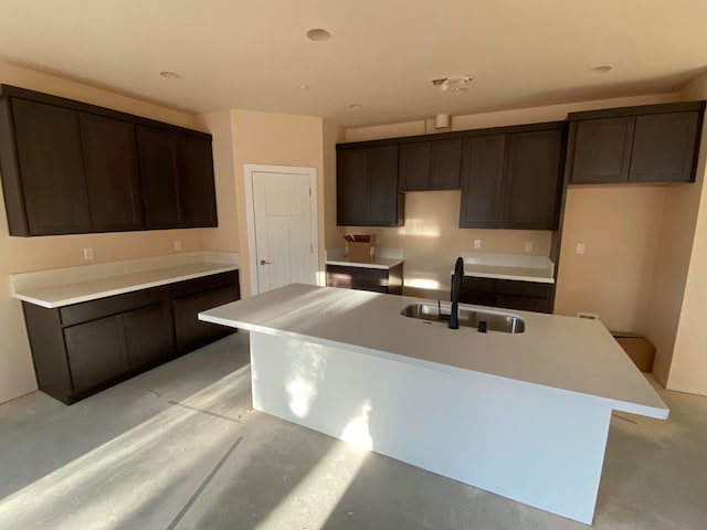 kitchen with sink, dark brown cabinets, and an island with sink