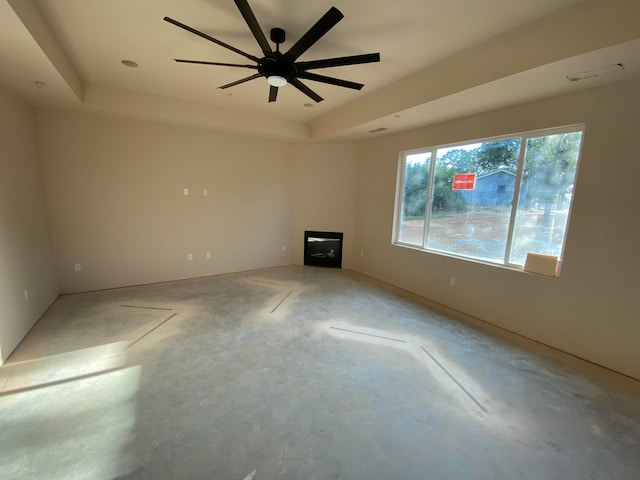 unfurnished living room featuring concrete flooring, a raised ceiling, and ceiling fan