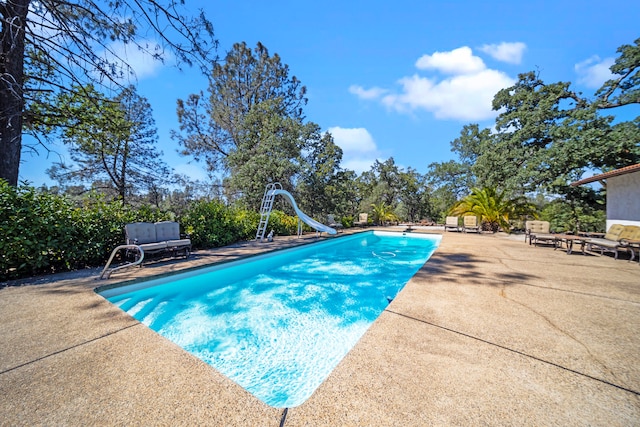 view of swimming pool with a patio area, a water slide, and a diving board