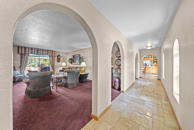 corridor with a textured ceiling and light colored carpet