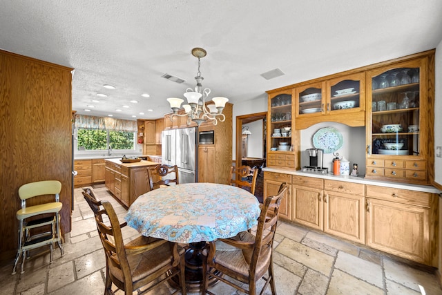 dining area with sink, a notable chandelier, and a textured ceiling