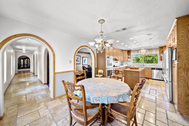 dining room with a textured ceiling, sink, and a chandelier