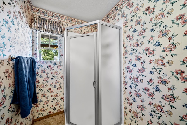 bathroom with a shower with door and a textured ceiling