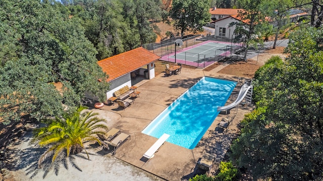 view of swimming pool with a patio, a water slide, and a diving board