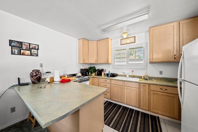 kitchen with kitchen peninsula, range, light tile patterned flooring, white fridge, and sink