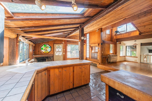 kitchen with tile countertops, vaulted ceiling with skylight, and a wealth of natural light