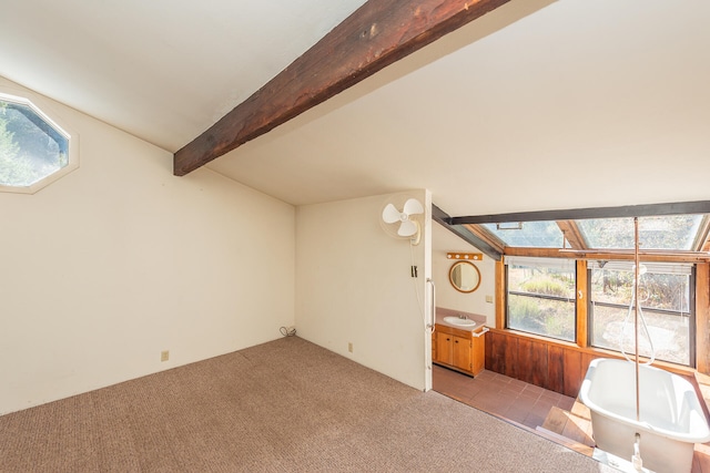 unfurnished living room featuring vaulted ceiling with beams and light colored carpet