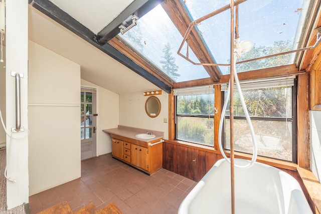 bathroom with vanity, lofted ceiling with beams, a bathtub, and wood walls