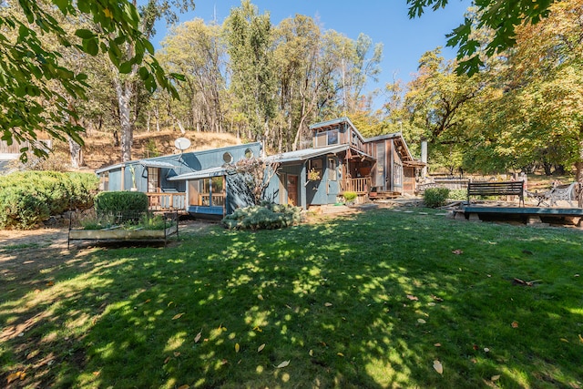 back of house with a deck and a lawn