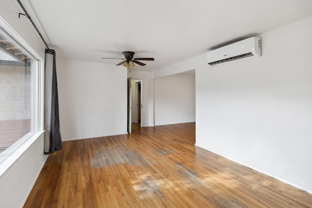 empty room featuring a wall mounted air conditioner, ceiling fan, and light wood-type flooring