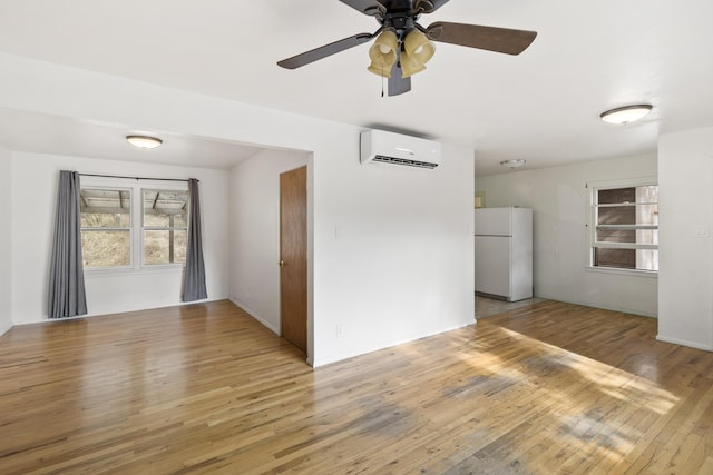 unfurnished room featuring an AC wall unit, ceiling fan, and hardwood / wood-style floors