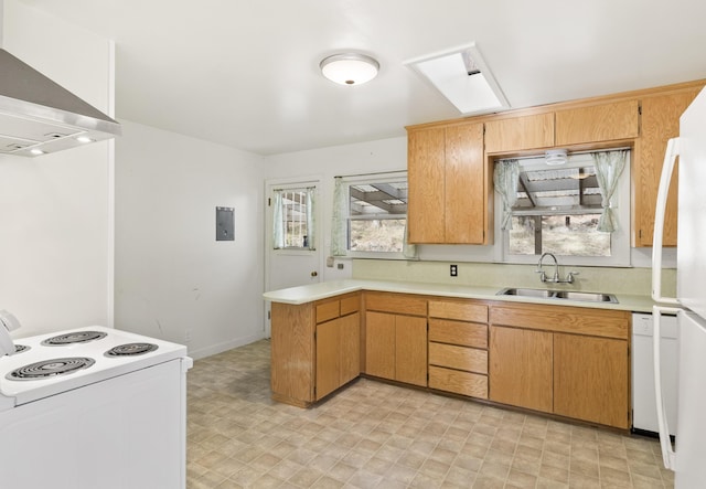 kitchen with a skylight, sink, wall chimney range hood, kitchen peninsula, and white appliances