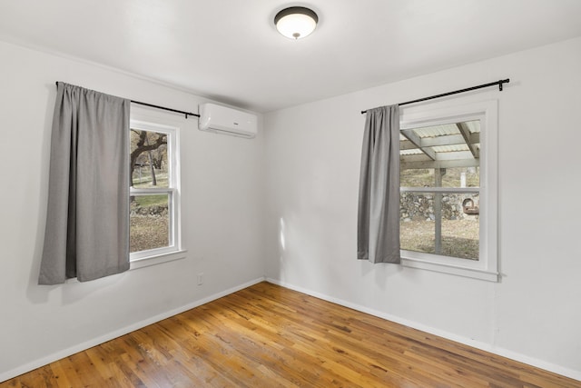 empty room with a wall unit AC, wood-type flooring, and a wealth of natural light