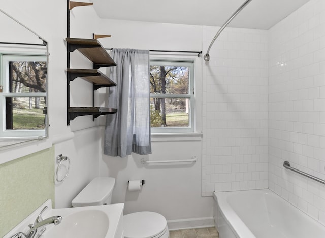 full bathroom featuring sink, tiled shower / bath combo, and toilet