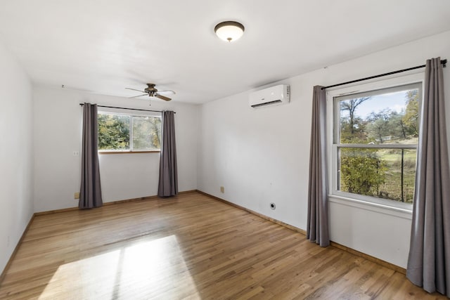 unfurnished room with ceiling fan, an AC wall unit, and light hardwood / wood-style flooring