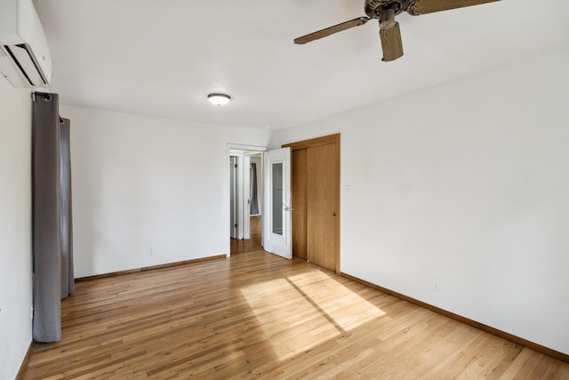 spare room with hardwood / wood-style floors, ceiling fan, and an AC wall unit